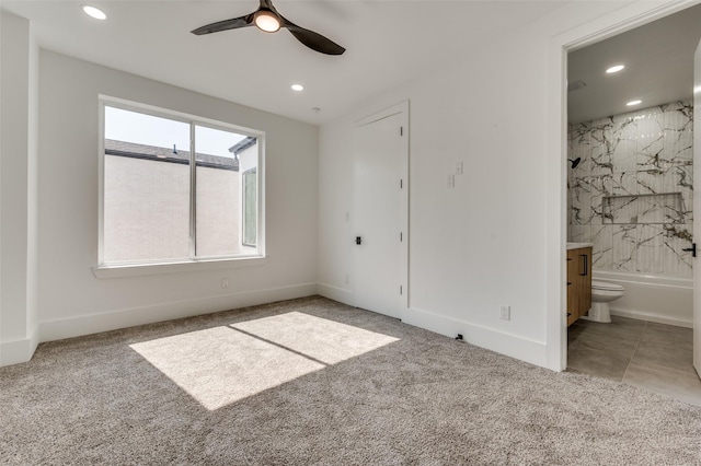 unfurnished bedroom featuring light carpet, ensuite bathroom, and ceiling fan