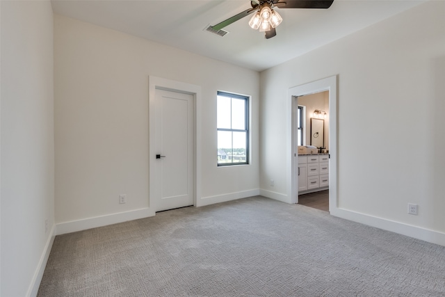 unfurnished bedroom with ensuite bathroom, ceiling fan, and light colored carpet