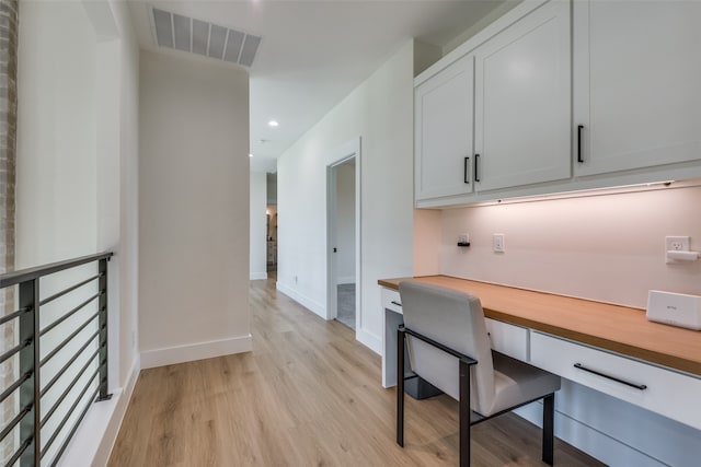 home office with built in desk and light hardwood / wood-style flooring