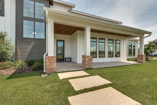 entrance to property with covered porch and a yard