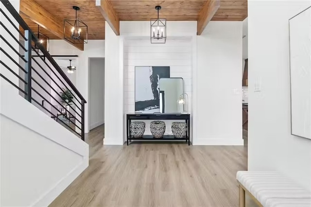 foyer entrance featuring beamed ceiling, wooden ceiling, light wood-type flooring, and an inviting chandelier