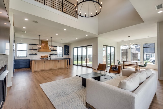 living room featuring light wood-type flooring, sink, and a chandelier