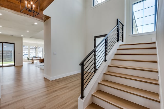 staircase with hardwood / wood-style floors and a notable chandelier