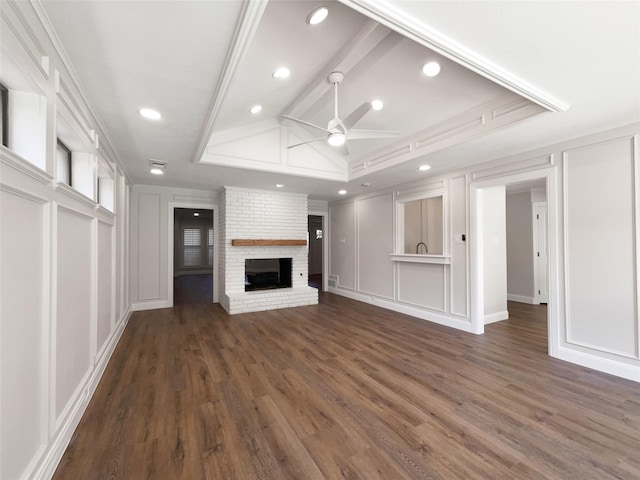 unfurnished living room featuring dark wood-type flooring, a brick fireplace, ceiling fan, ornamental molding, and a tray ceiling