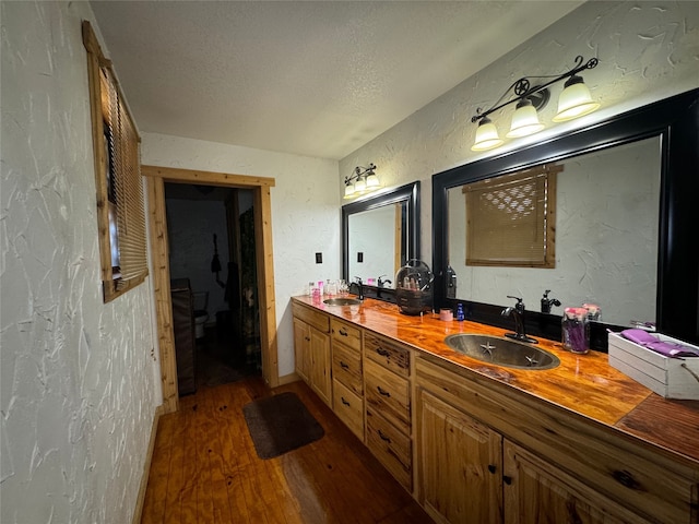 bathroom with hardwood / wood-style flooring, vanity, and a textured ceiling