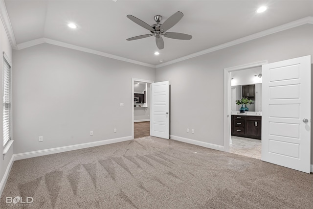 unfurnished bedroom featuring ensuite bath, light colored carpet, lofted ceiling, ceiling fan, and ornamental molding