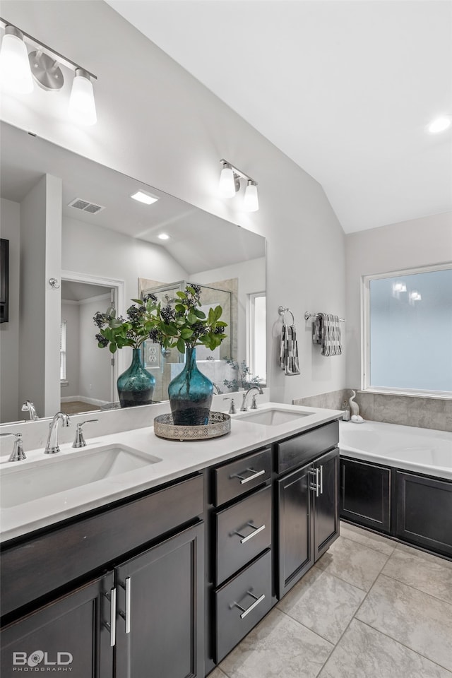 bathroom with double vanity, a tub to relax in, lofted ceiling, and tile patterned floors