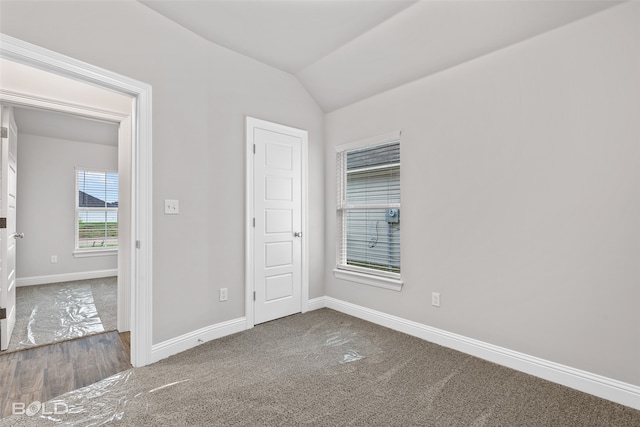 unfurnished bedroom with lofted ceiling and dark colored carpet