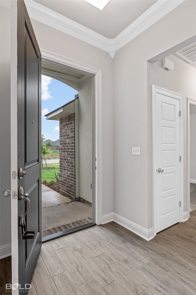 foyer entrance featuring crown molding and light wood-type flooring