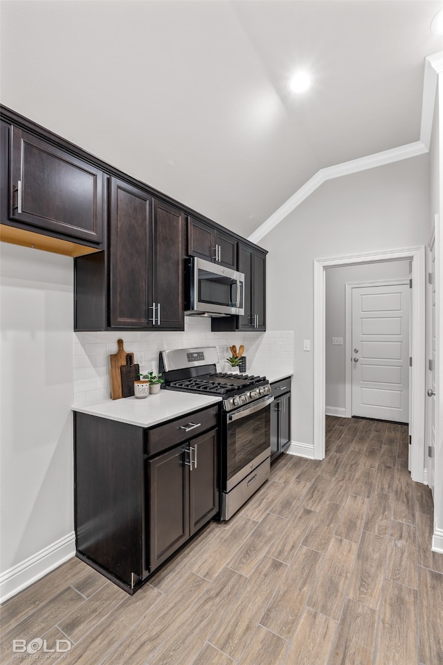 kitchen with stainless steel appliances, dark brown cabinets, light hardwood / wood-style floors, decorative backsplash, and ornamental molding