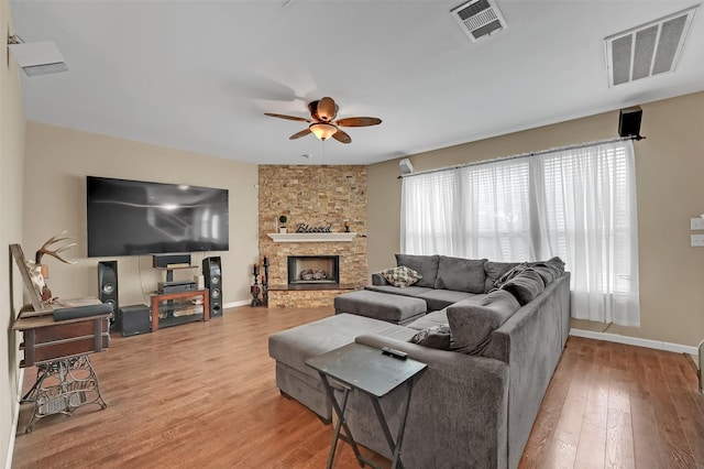 living room featuring ceiling fan, a fireplace, and light wood-type flooring