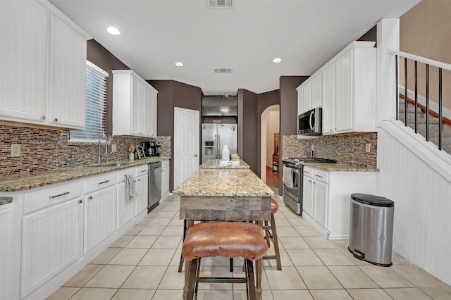 kitchen with a sink, decorative backsplash, white cabinetry, appliances with stainless steel finishes, and visible vents