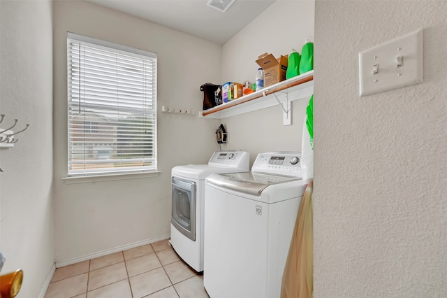 laundry area with washing machine and clothes dryer and light tile patterned flooring