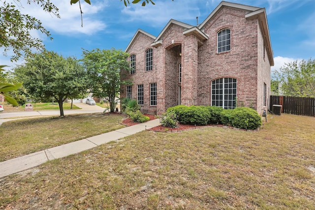traditional home with fence, brick siding, and a front yard