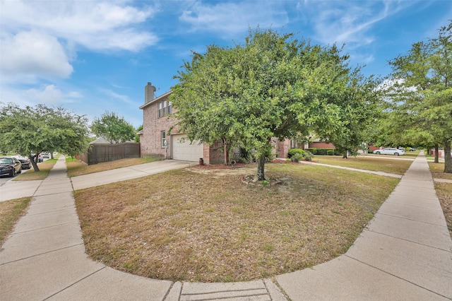view of front of home featuring a front lawn, driveway, a chimney, fence, and a garage