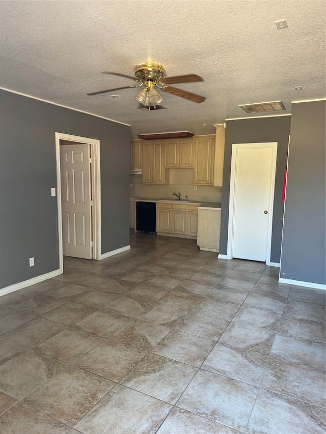 kitchen with ceiling fan, sink, a textured ceiling, and light brown cabinetry