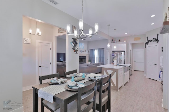 dining space with light wood-type flooring, an inviting chandelier, and sink