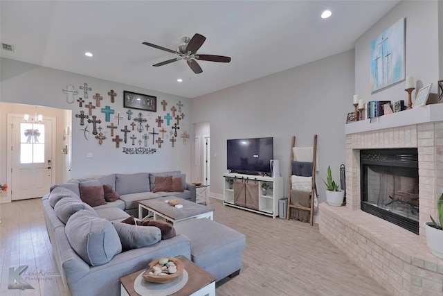 living room with ceiling fan, light hardwood / wood-style flooring, and a brick fireplace