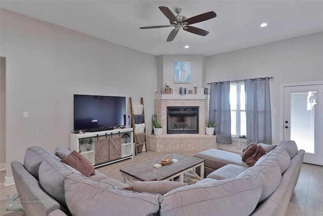 living room featuring a brick fireplace, a healthy amount of sunlight, and light hardwood / wood-style floors