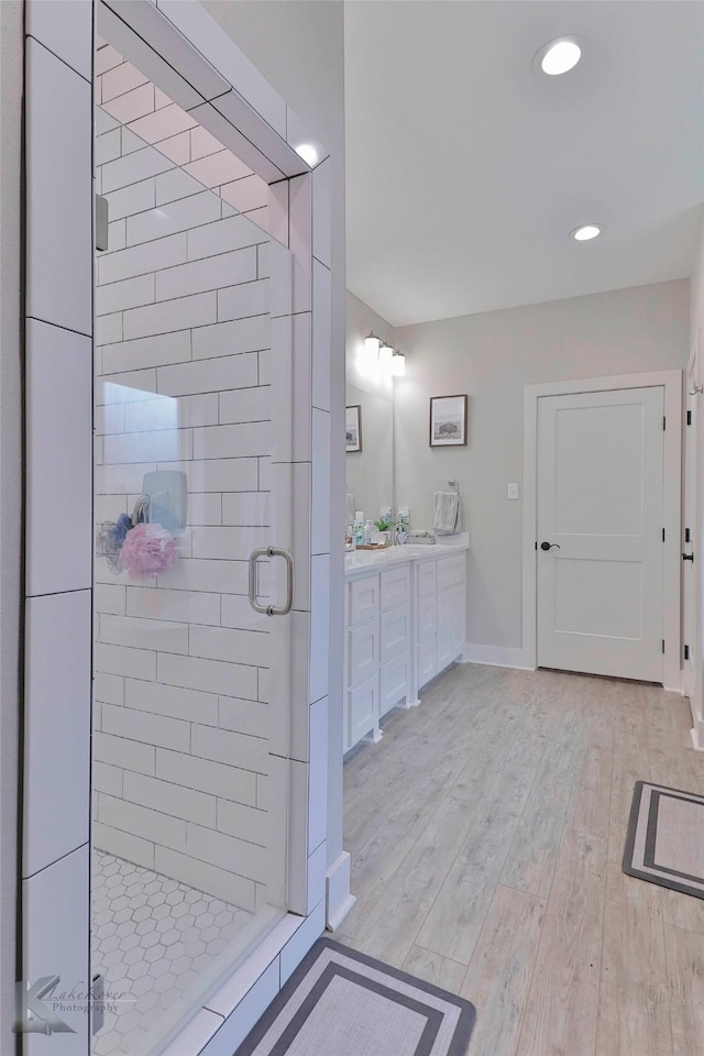 bathroom with hardwood / wood-style flooring, vanity, and an enclosed shower