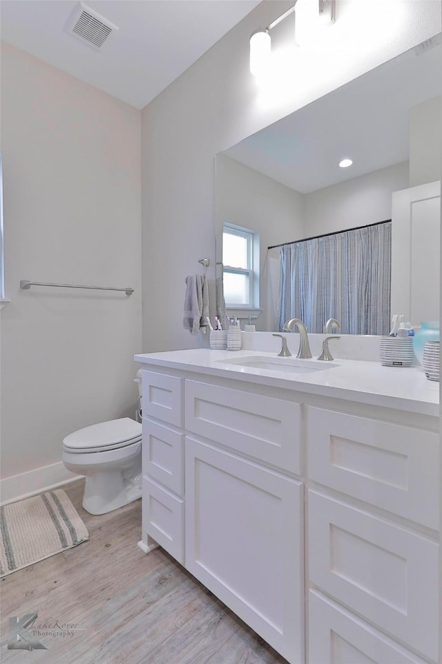 bathroom featuring a shower with shower curtain, hardwood / wood-style floors, vanity, and toilet