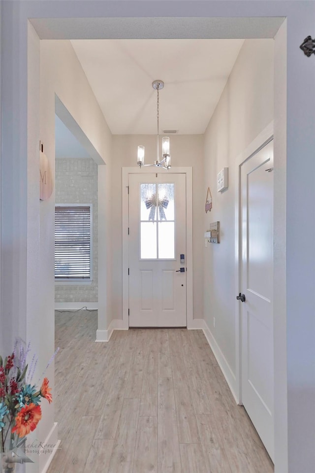 foyer entrance featuring light hardwood / wood-style flooring and a notable chandelier