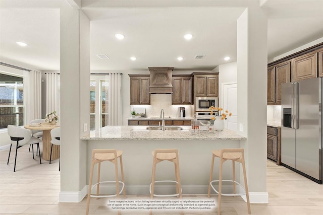 kitchen featuring sink, stainless steel appliances, light stone counters, kitchen peninsula, and a breakfast bar area