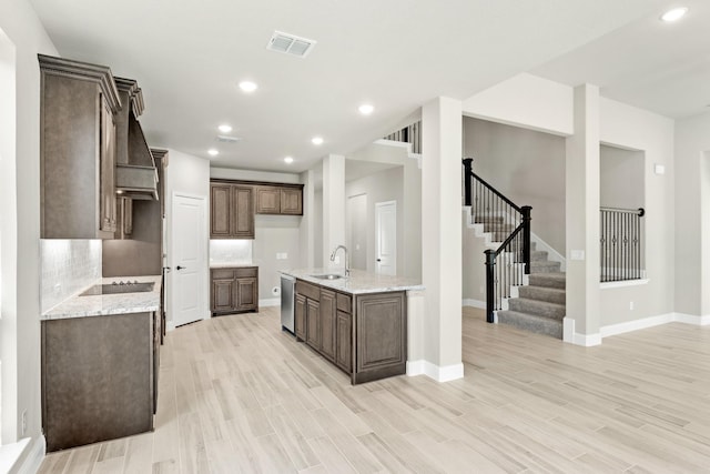 kitchen featuring tasteful backsplash, light stone countertops, stainless steel dishwasher, and light hardwood / wood-style floors