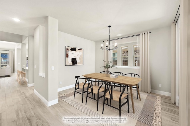 dining space with light wood-type flooring and a notable chandelier