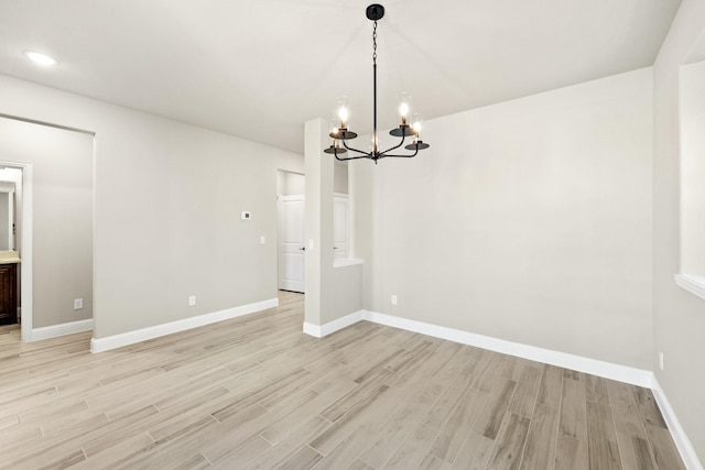 unfurnished dining area featuring light hardwood / wood-style floors and a notable chandelier