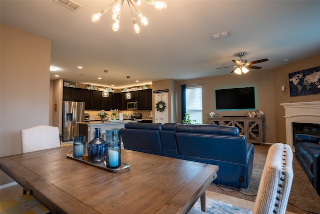 dining space with ceiling fan with notable chandelier