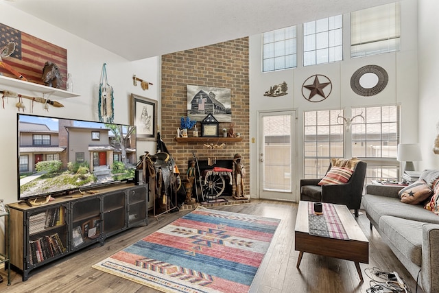 living room with brick wall, a brick fireplace, hardwood / wood-style flooring, and a high ceiling