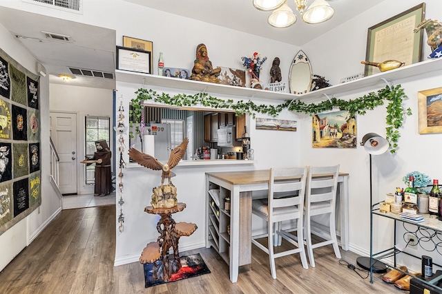 kitchen with built in microwave, hardwood / wood-style flooring, white refrigerator, and an inviting chandelier