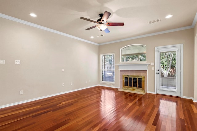 unfurnished living room featuring a tiled fireplace, wood-type flooring, and ornamental molding