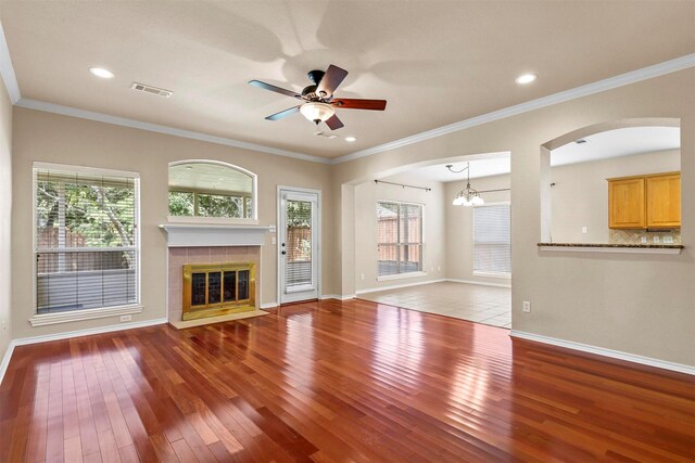 unfurnished living room with ceiling fan with notable chandelier, light hardwood / wood-style flooring, and ornamental molding