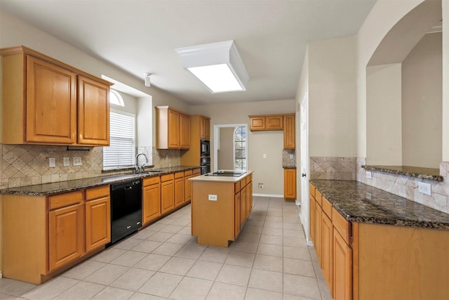 kitchen featuring light tile patterned flooring, sink, dark stone countertops, a kitchen island, and black appliances