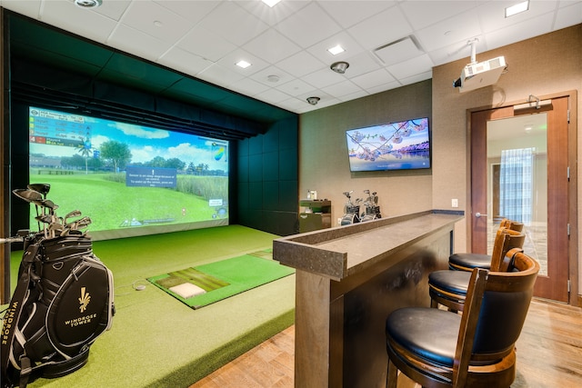 playroom featuring golf simulator, a drop ceiling, and light hardwood / wood-style flooring