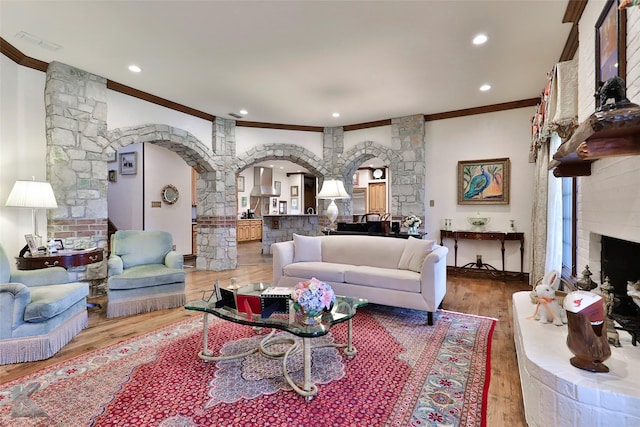 living room featuring a large fireplace, crown molding, and light hardwood / wood-style flooring