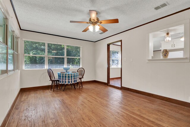 dining space featuring light wood-type flooring, crown molding, and a textured ceiling