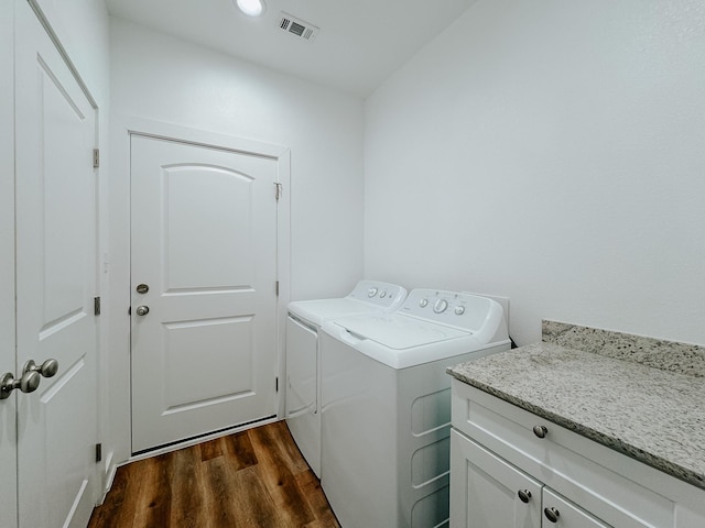 clothes washing area featuring cabinets, dark hardwood / wood-style floors, and washing machine and clothes dryer