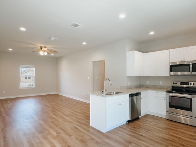 kitchen with sink, light hardwood / wood-style flooring, kitchen peninsula, white cabinets, and appliances with stainless steel finishes