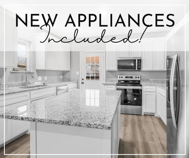 kitchen with appliances with stainless steel finishes, a center island, sink, and white cabinets