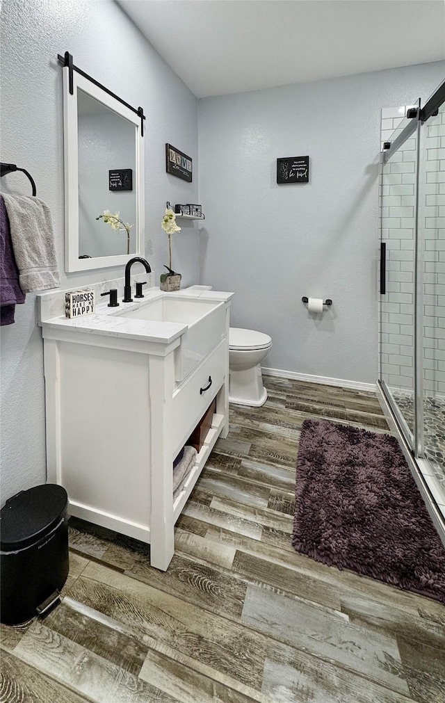 bathroom with wood-type flooring, vanity, toilet, and walk in shower