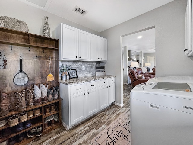 laundry area with independent washer and dryer, cabinets, and wood-type flooring