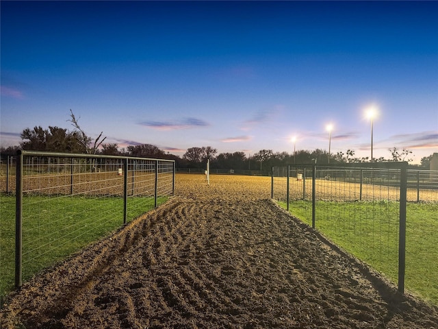 yard at dusk featuring a rural view