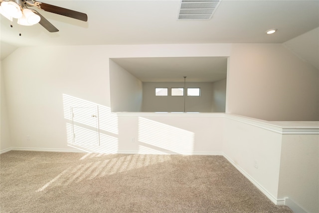 empty room with vaulted ceiling, carpet floors, and ceiling fan