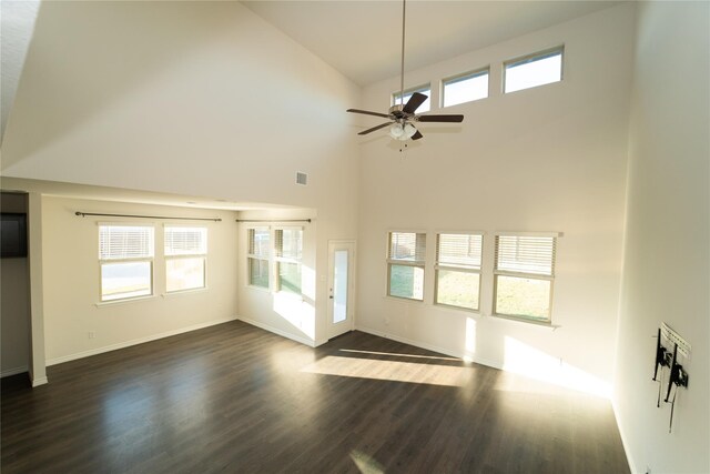 unfurnished living room featuring dark wood-type flooring, a healthy amount of sunlight, and a high ceiling