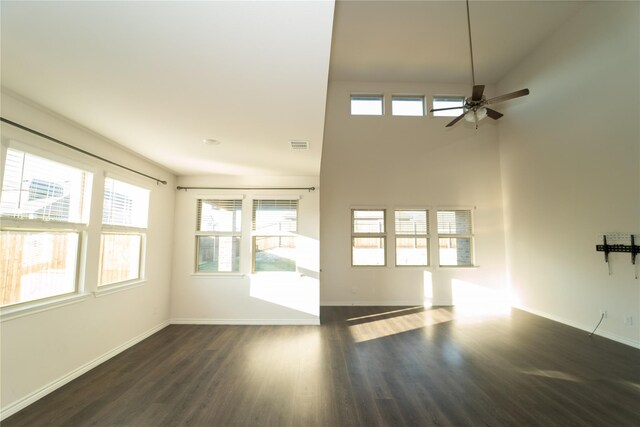 unfurnished living room with high vaulted ceiling, a healthy amount of sunlight, ceiling fan, and dark hardwood / wood-style floors