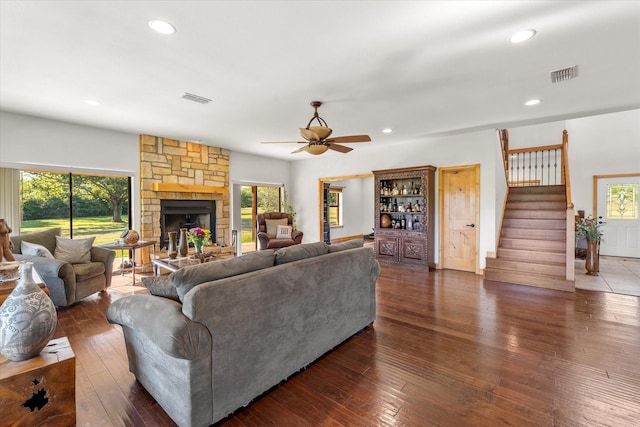 living room with a stone fireplace, ceiling fan, and dark hardwood / wood-style flooring