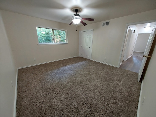 unfurnished bedroom with dark colored carpet, ceiling fan, and a closet